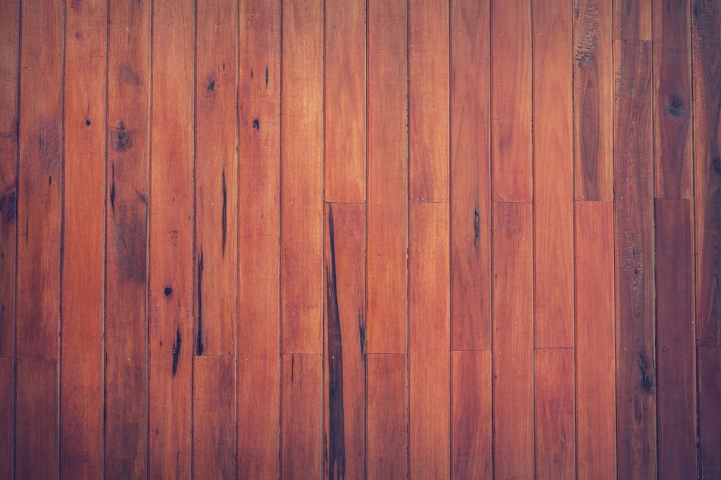 Close-up view of a rustic wooden plank floor with rich brown tones and visible wood grain.